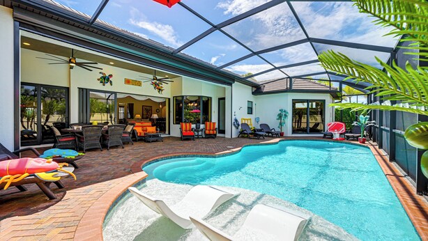 A covered outdoor swimming pool with lounge chairs and a patio area.