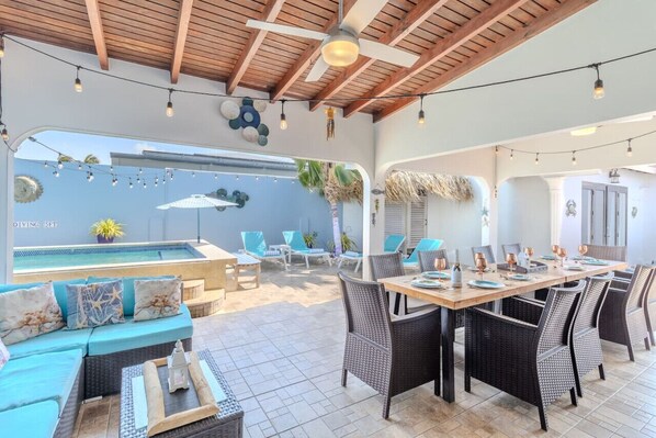 An outdoor patio with a pool, lounge chairs, and a dining area with wicker furniture.