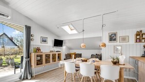 Eine moderne Küche mit Essbereich, Holzschränken und einem großen Fenster.