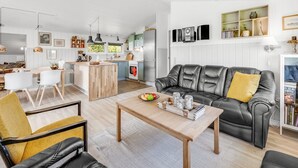Ein modernes Wohnzimmer mit einer Ledersofa, einem Holztisch und einem Essbereich mit weißen Stühlen.