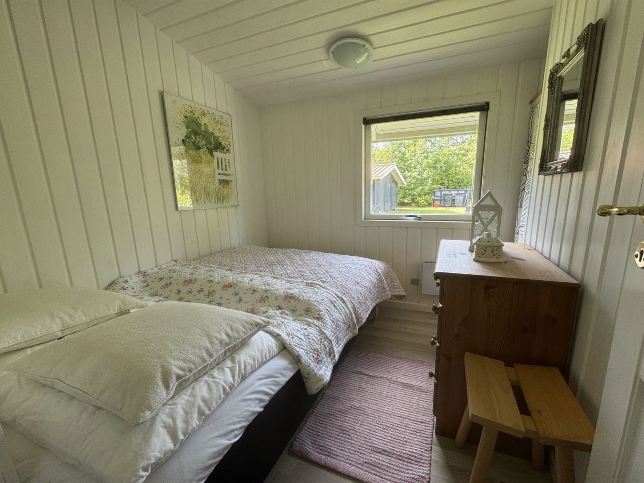 A bedroom with a bed, a dresser, a window, and a door.