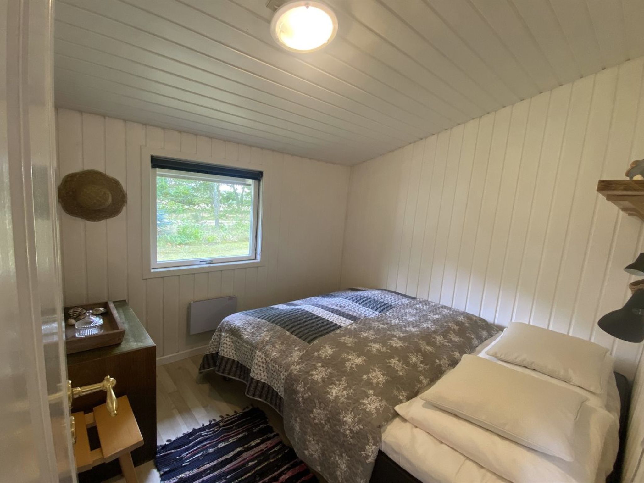 Ein Schlafzimmer mit Bett, Fenster, Heizkörper, Nachttisch, Lampe und Sessel.