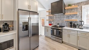 Una cucina moderna con elettrodomestici in acciaio inossidabile, un dispenser integrato per l'acqua e una cucina a gas.