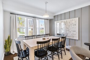 A dining area with a table, chairs, a potted plant, and a wall with a cityscape drawing. - Upscale 5BR/3BA w/ Jacuzzi (Oak Park)