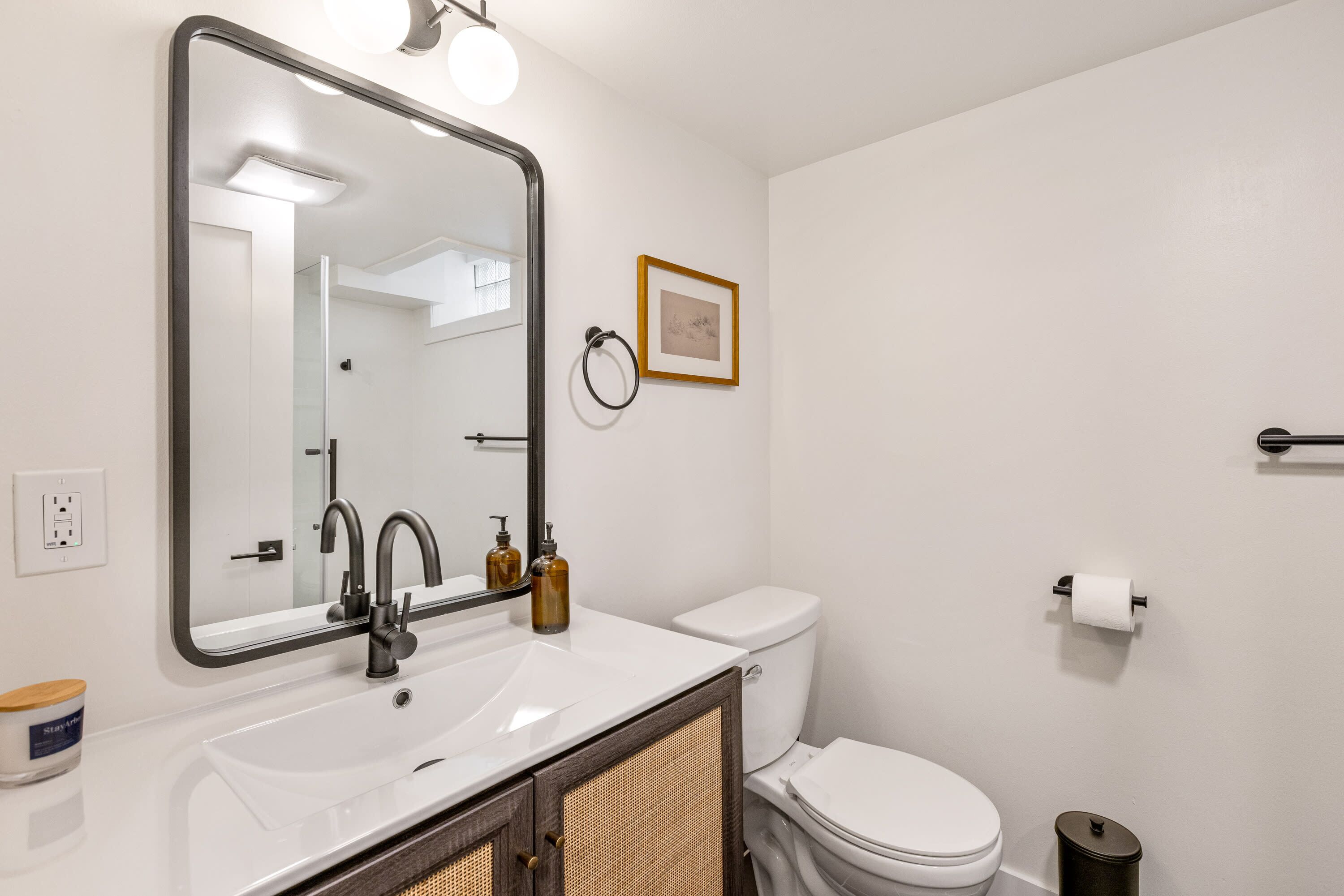 Une salle de bain moderne avec un grand miroir, un lavabo blanc et des toilettes.
