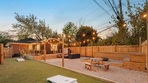 Un giardino sul retro con un patio in legno, posti a sedere all'aperto e luci decorative.