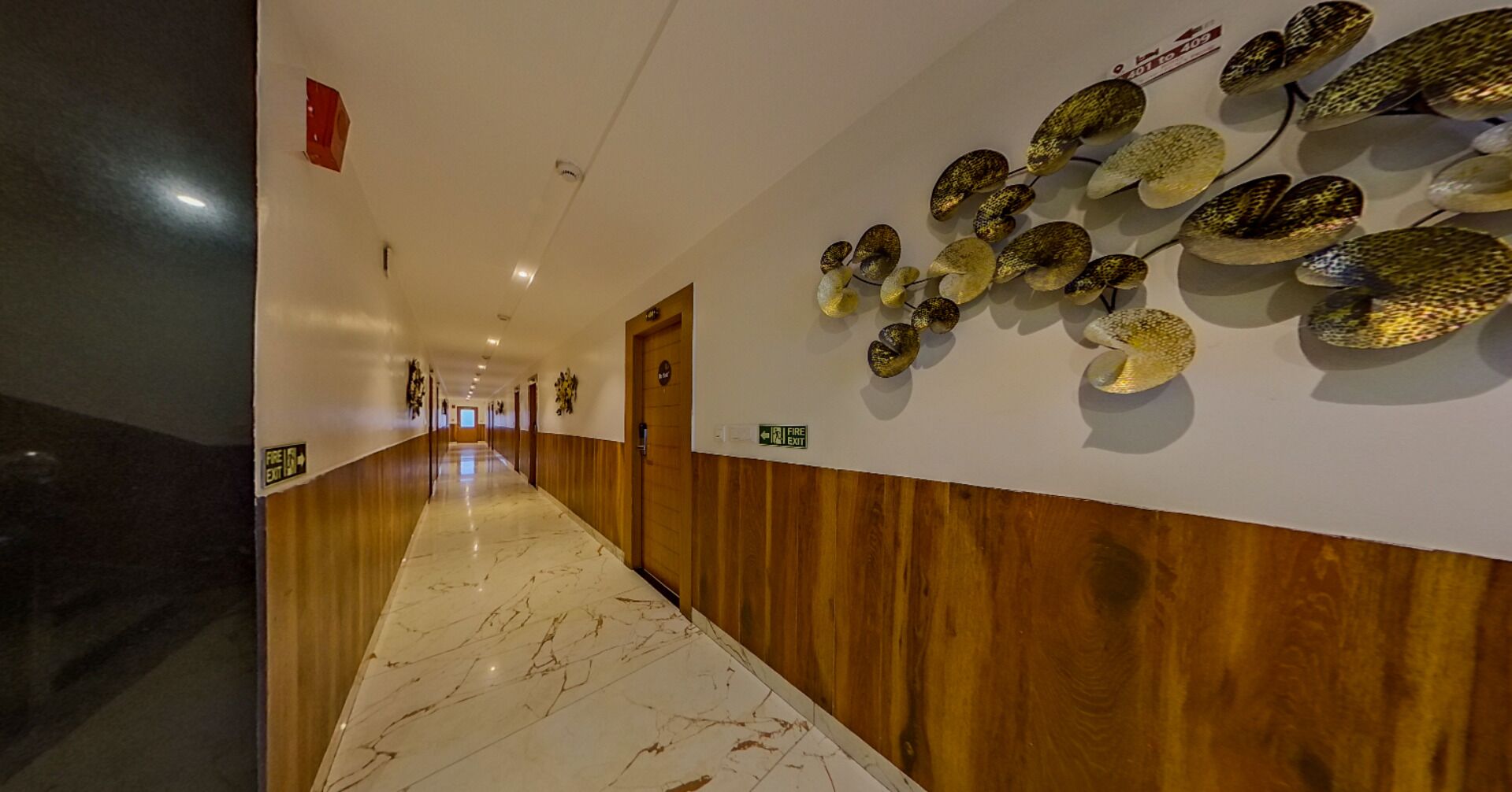 A hotel hallway with a marble floor, wooden paneling, and a wall-mounted decorative piece.