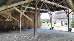 A covered outdoor area with a gravel floor, wooden benches, and a rustic wooden wall. - Albertine's bed and breakfast near Sancerre Guédelon and St Fargeau (LERE)