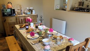 A dining table set with food and drinks, a microwave, and a wooden bench. - Albertine's bed and breakfast near Sancerre Guédelon and St Fargeau (LERE)