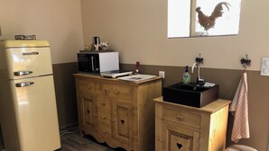 A kitchenette with a vintage refrigerator, microwave, and toaster, wooden cabinets, a sink with a faucet, and a window with a rooster decoration. - Albertine's bed and breakfast near Sancerre Guédelon and St Fargeau (LERE)