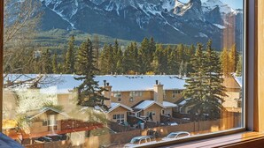A window with a view of snow-covered mountains and houses.