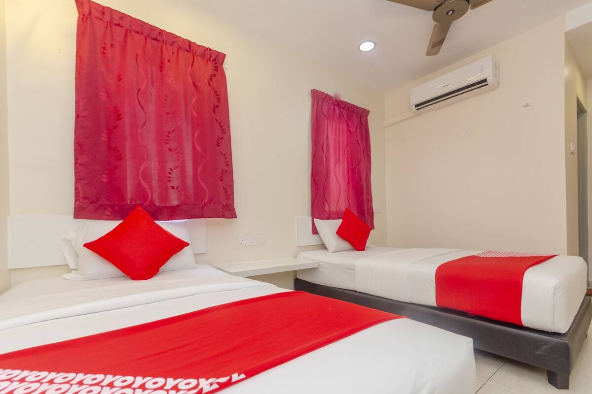 Habitación de hotel con dos camas, ropa de cama roja y blanca y cortinas rojas.