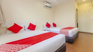 Habitación de hotel con dos camas, cada una con ropa de cama roja y blanca, y un corredor de cama con estampado rojo y blanco.