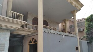A two-story building with a balcony, columns, and potted plants. - M M Palace Guest House Peshawar (Peshawar)
