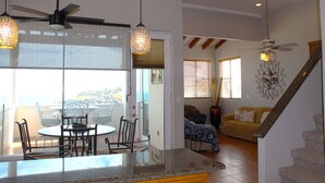 Amplia sala de estar con una mesa y sillas de comedor, un sofá y una escalera que lleva a un nivel superior.