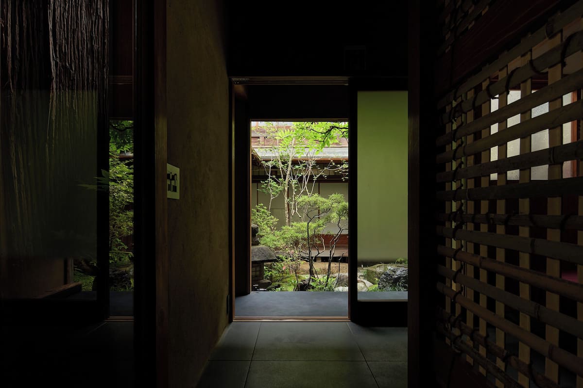 A traditional Japanese interior with a wooden sliding door leading to a garden.