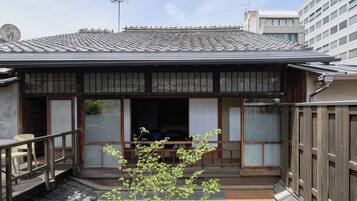 A traditional Japanese-style building with a tiled roof, wooden exterior, and a small porch area.
