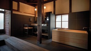 A modern bathroom with a wooden bathtub, a sink, and a mirror. - Kyo no Yado Ishihara (Kyoto)