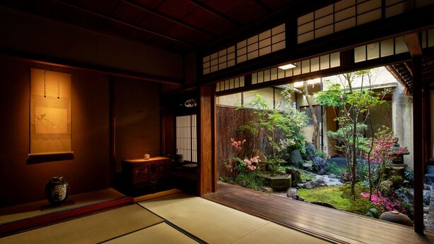 A traditional Japanese room with tatami flooring, a shoji screen door, and a small garden visible through the door. - Kyo no Yado Ishihara (Kyoto)