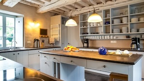 Una cocina con una isla central, armarios blancos, una cafetera y un frutero.