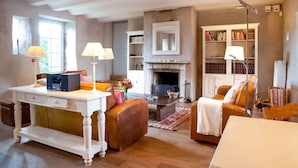 Un amplio salón con chimenea, una consola blanca, sofás de cuero y una estantería.