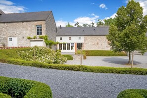 A stone building with a gravel driveway and well-maintained hedges. - Getaway with Sauna in Falaën (Maredsous)