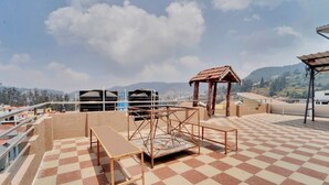 A rooftop terrace with a checkered floor, metal furniture, and a small shelter.