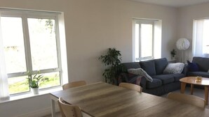 A living room with a wooden dining table, two sofas, and a potted plant. - Central Spacious 3 Bedroom Apartment With Parking (Dublin)