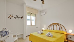 A room with a bed, a chair, a table, a window, and a wall-mounted air conditioner. - Villa Dei Fanti - Beachfront Villa With Garden (Lecce)