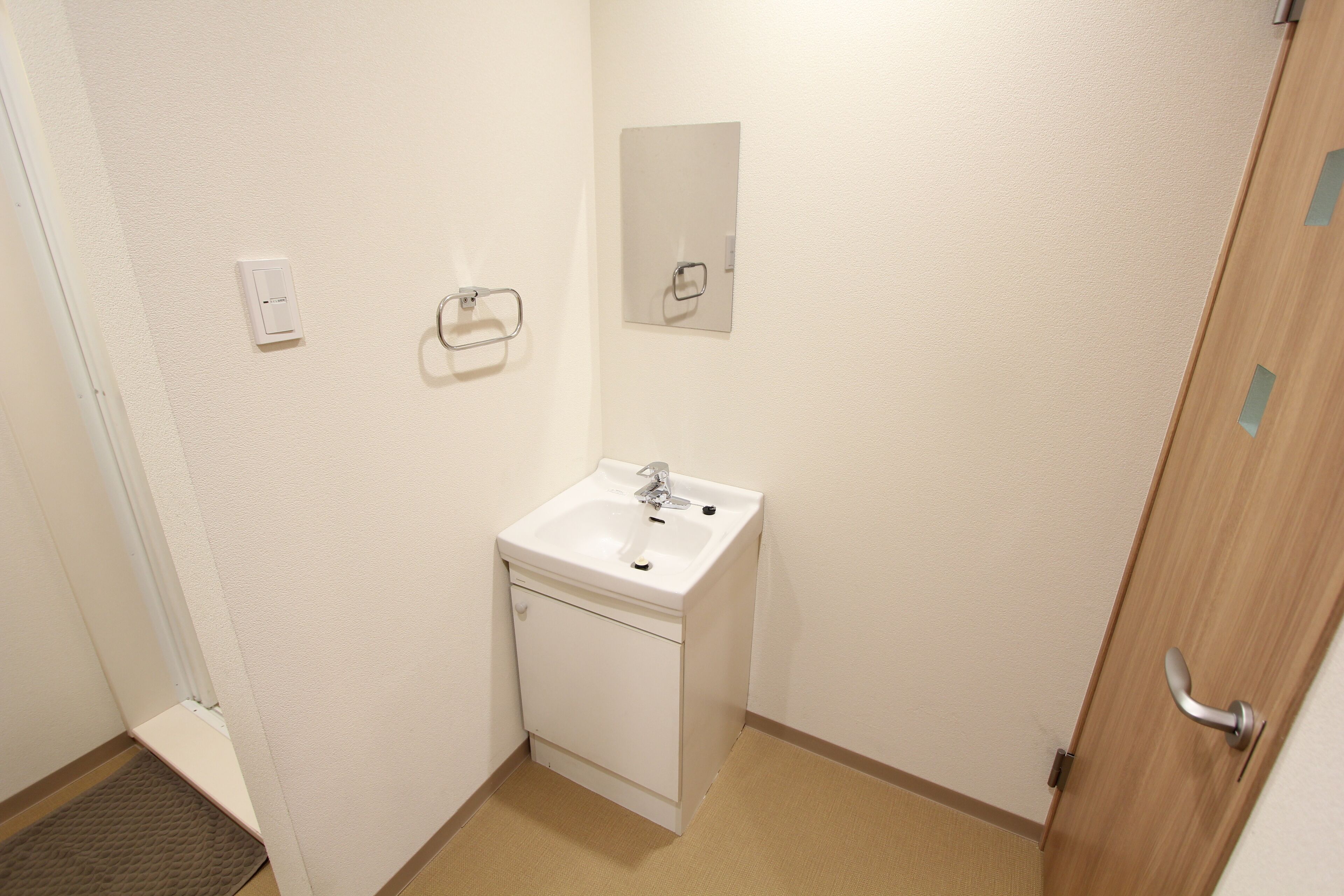 Een kleine badkamer met een wit wastafelmeubel, een spiegel en een handdoekhouder.
