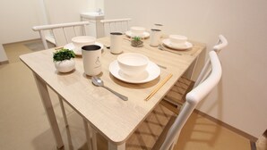 A dining table set with white dishes, a small plant, and chopsticks. - LUANA Koenji (Tokyo)