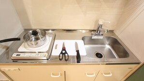 A kitchen with a stove, a sink, and a countertop with a pot, a pair of scissors, and a knife. - LUANA Koenji (Tokyo)