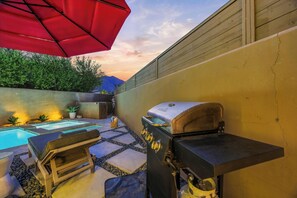 Un jardin avec une piscine, un barbecue et un espace salon extérieur.