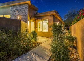 Una casa moderna con fachada de piedra, puerta de cristal y un cielo nocturno estrellado.