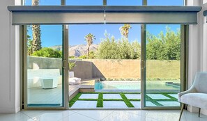 A modern interior with a sliding glass door leading to an outdoor pool area. - Stunning Modern Oasis - Heated Pool & Spa · Mountain Views · 5min to Downtown! (Palm Springs)