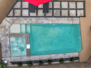 A swimming pool with a tiled deck area, a red umbrella, and potted plants. - Stunning Modern Oasis - Private Heated Pool & Spa · Mtn Views · 5min to Downtown (Palm Springs)