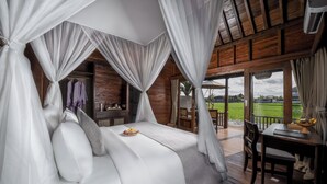 A bedroom with a canopy bed, a dining area, and a view of the outdoors. - Berlima Boutique Resort (Ubud)