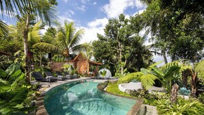 A pool area with lounge chairs, a small building, and lush tropical vegetation. - Berlima Boutique Resort (Ubud)