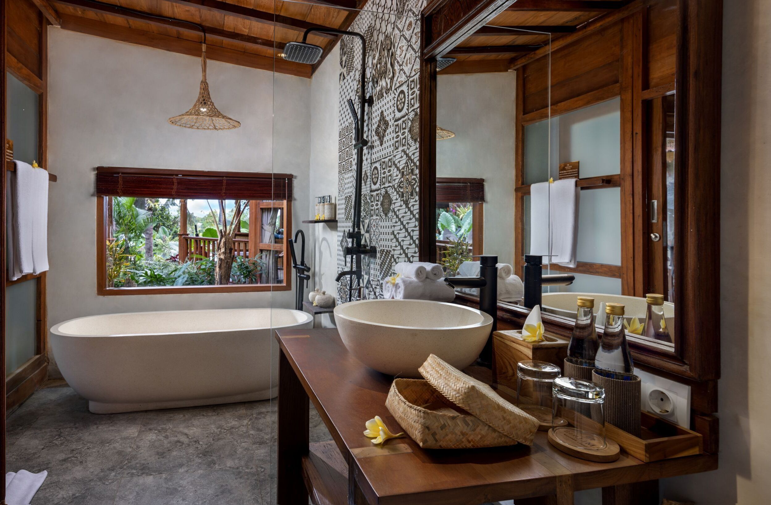 A bathroom with a freestanding bathtub, a large vessel sink, a wooden vanity, and a large mirror.