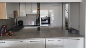 Una cocina moderna con gabinetes blancos, horno empotrado y encimera de granito.