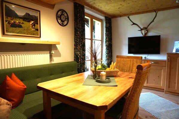 Un salon avec un canapé vert, une table en bois et un crâne de cerf accroché au mur.