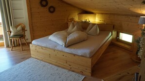 Un dormitorio de cabaña de madera con una cama, almohadas, una silla y una mesita.