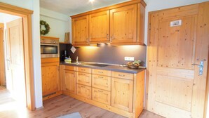 A kitchen with wooden cabinets, a built-in oven, and a stainless steel sink. - Ferienwohnung Veilchen für 2 Personen, 1 Separates Schlafzimmer, Balkon, 45m² (Inzell)