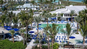 Een resort met een zwembad, omgeven door palmbomen en ligbedden.