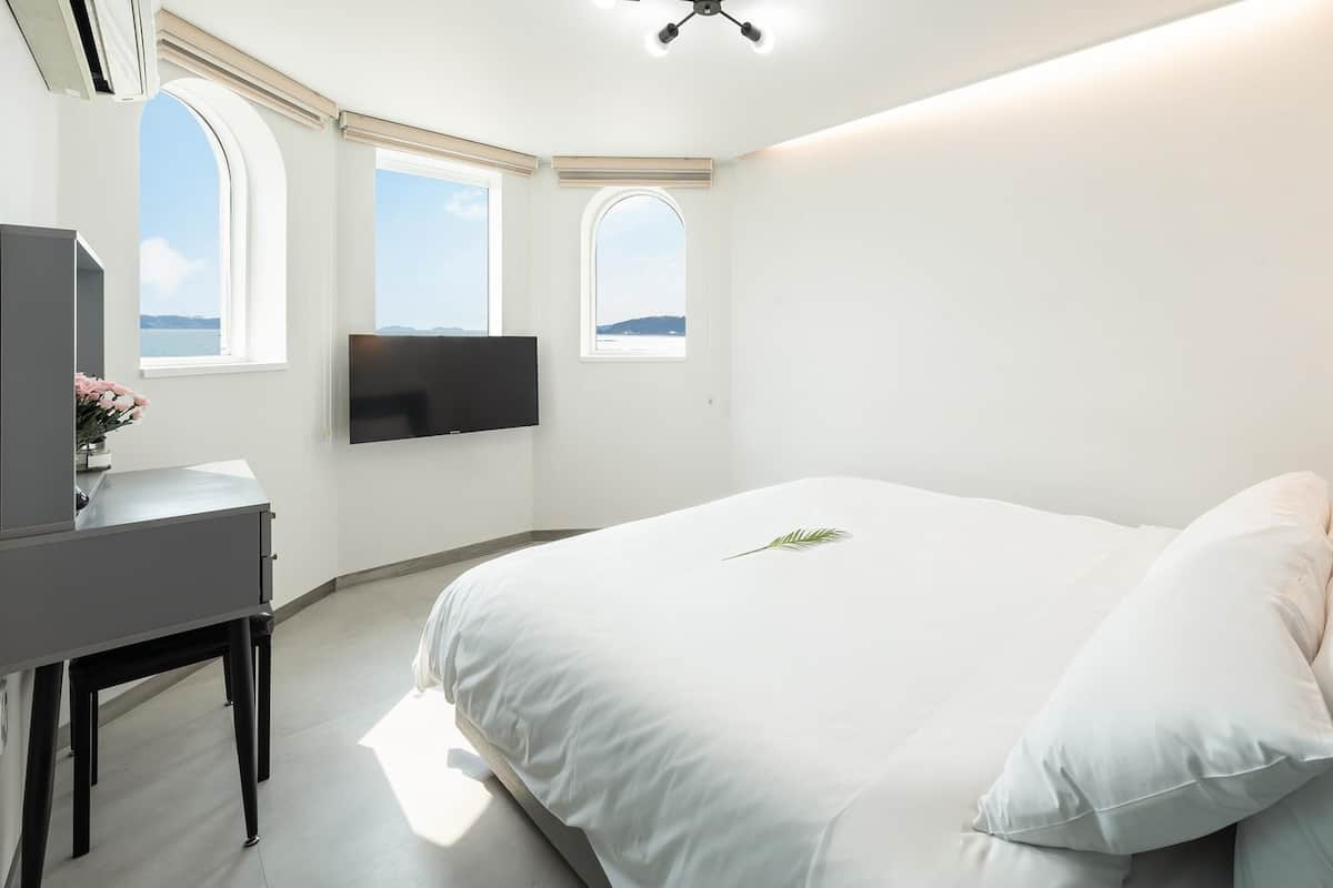 Ein modernes Schlafzimmer mit einem großen Bett, einem Schreibtisch und einem an der Wand befestigten Fernseher.