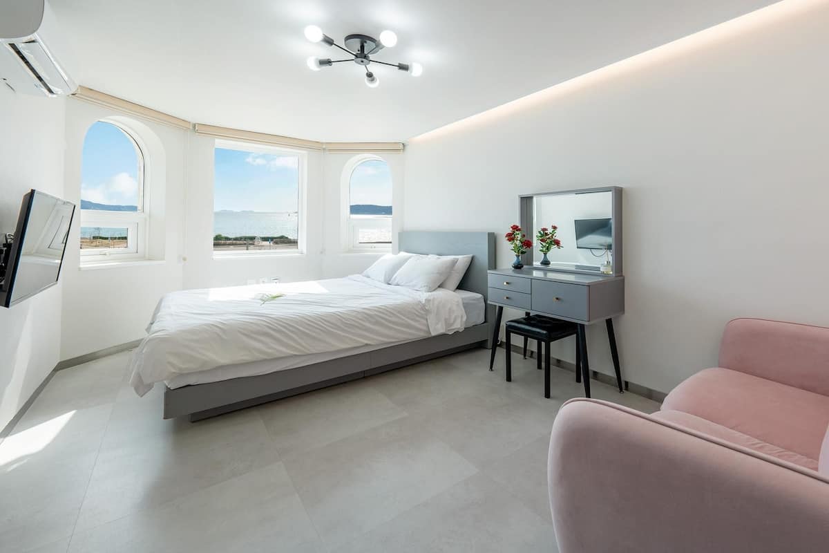 Ein modernes Schlafzimmer mit Bett, Schreibtisch, Stuhl und Fernseher.