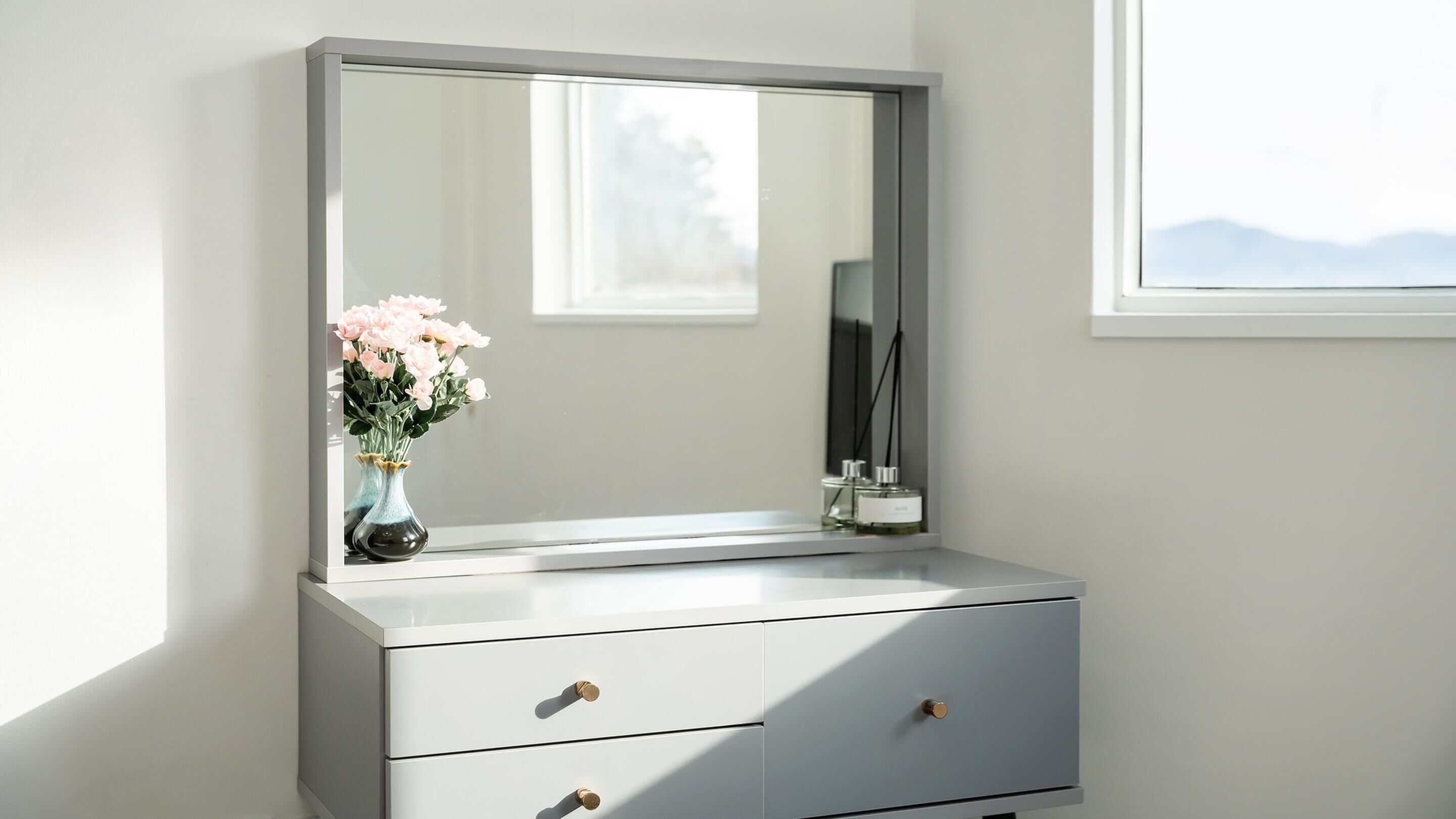 A bathroom vanity with a large mirror, two drawers, and a vase with flowers.