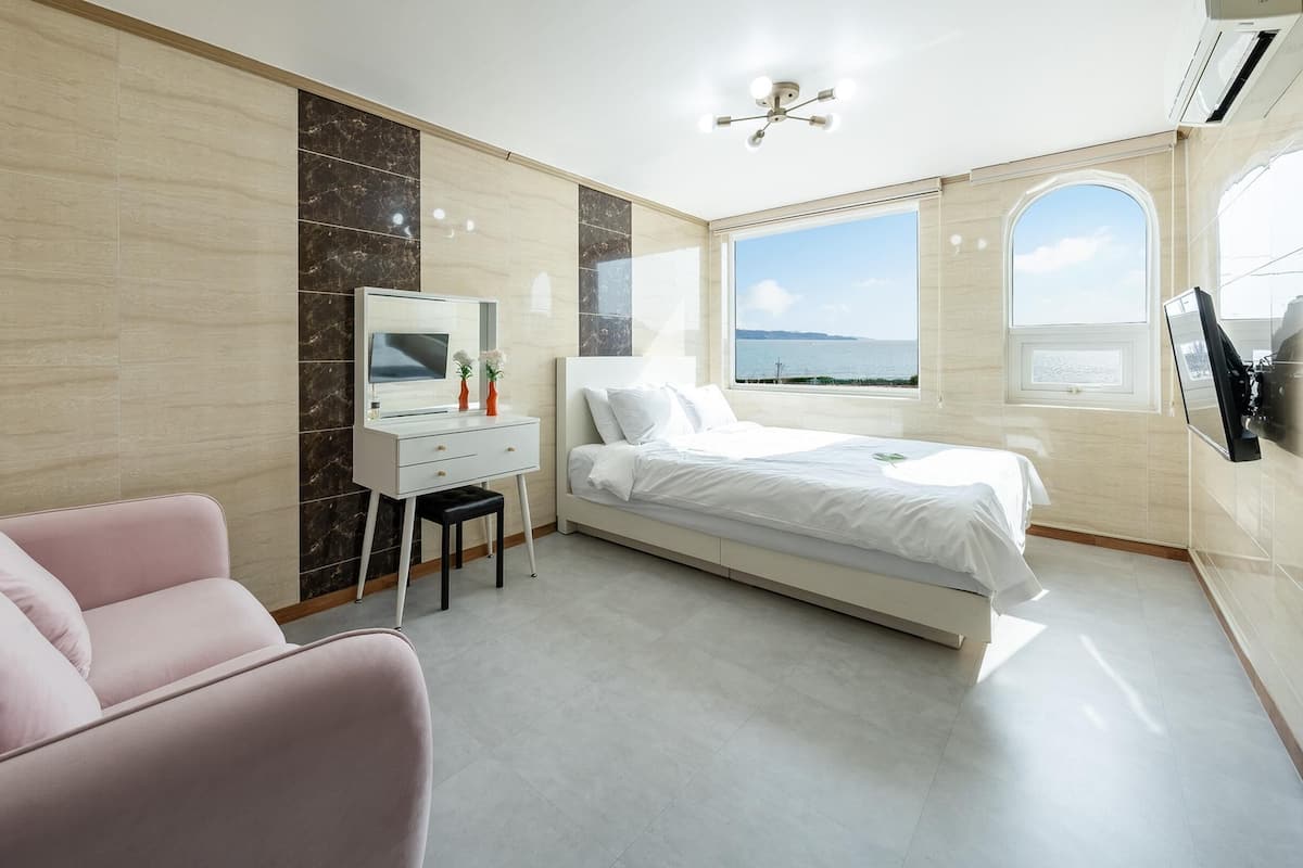 Ein modernes Schlafzimmer mit Bett, Schreibtisch, Stuhl und Fernseher.