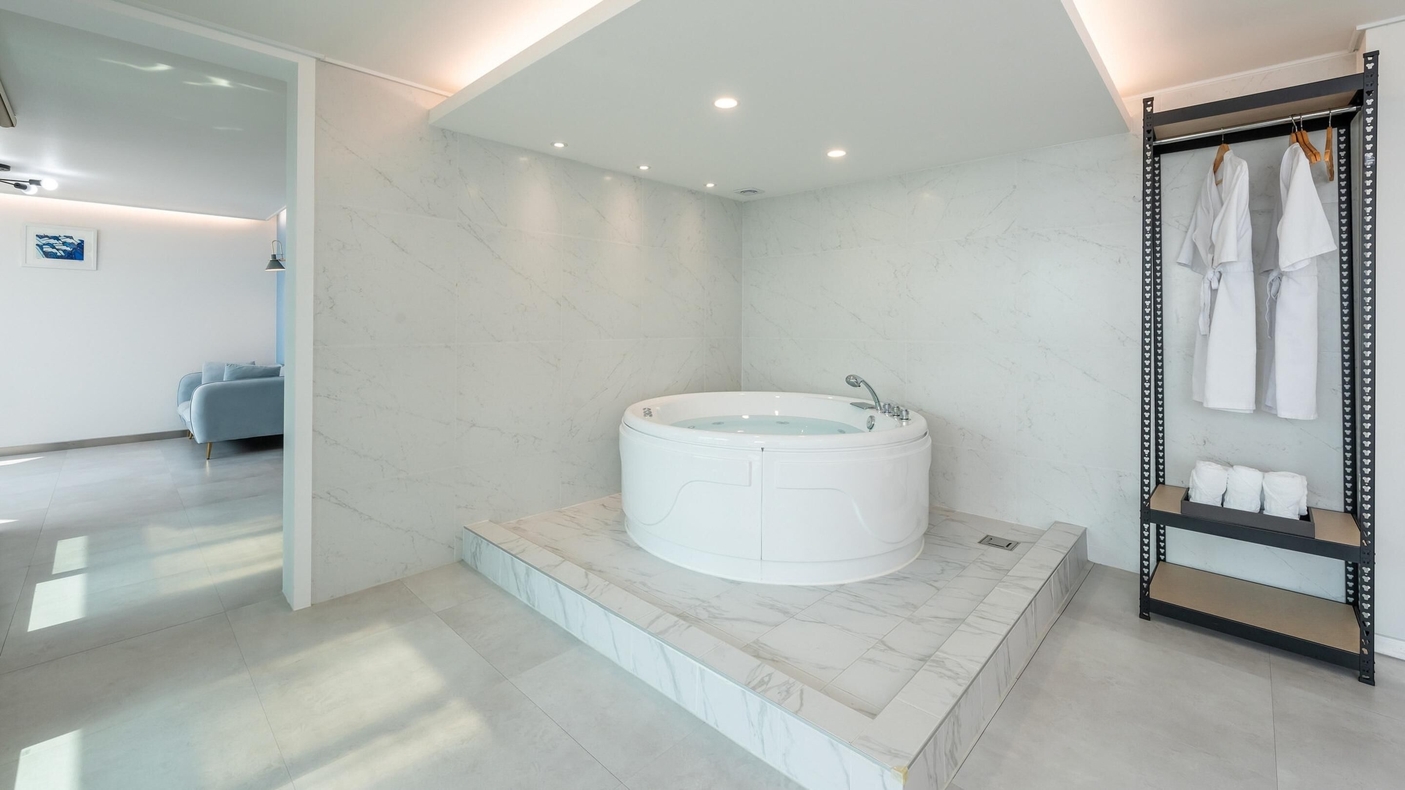 Une salle de bain moderne avec un sol en marbre, une baignoire sur pieds et un meuble-lavabo agrémenté de serviettes.