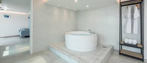 A modern bathroom with a marble floor, a freestanding bathtub, and a vanity with towels.